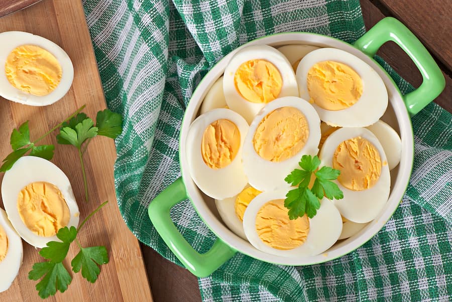 Halved hard-boiled eggs in a green bowl, a protein-rich healthy school snack