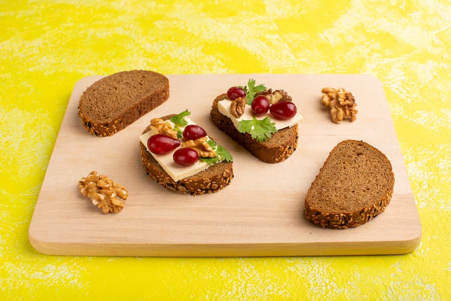 Mini whole-grain bread sandwiches with cheese on a wooden board, an easy healthy school snack