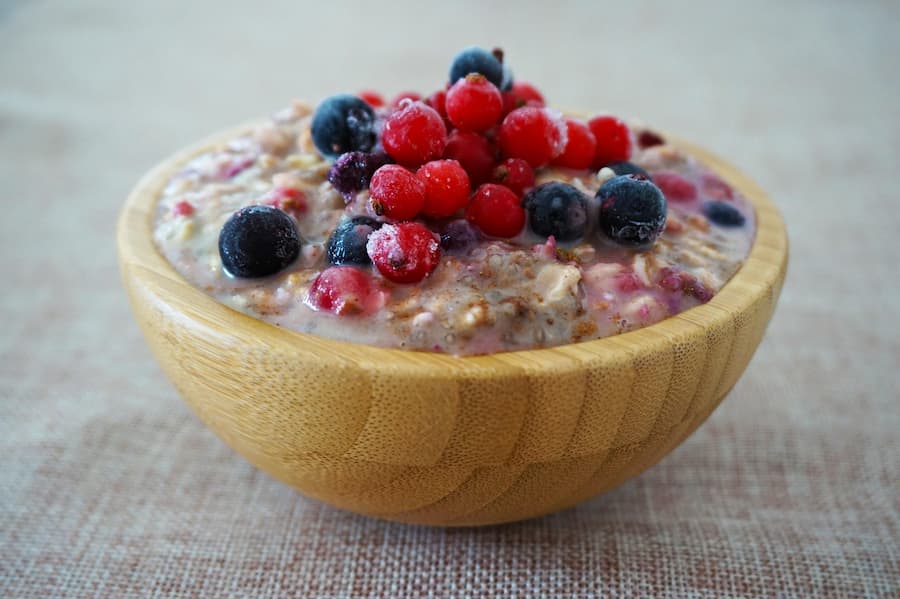 Wooden bowl of oatmeal topped with fresh blueberries and red berries
