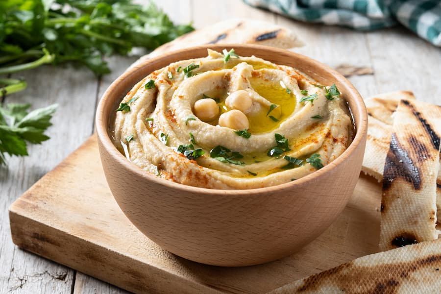 Creamy hummus with chickpeas in a wooden bowl served with pita bread, a healthy school snack