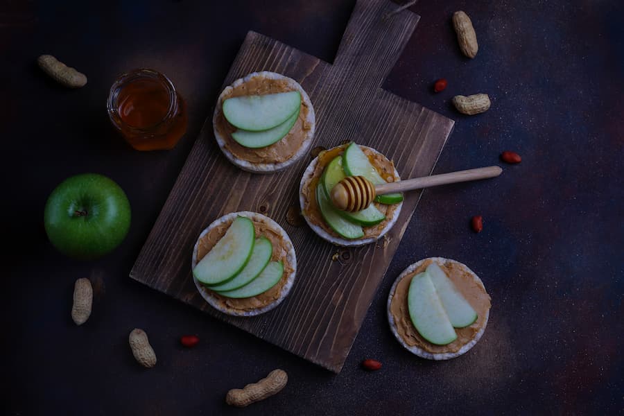 Apple slices with peanut butter on a dark wooden board