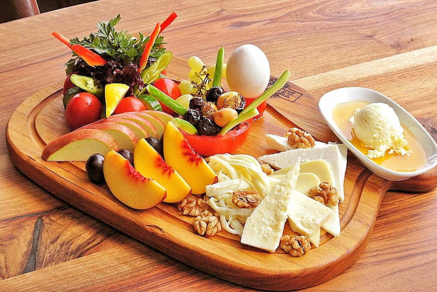 Wooden platter with cheese, fruits, crackers and vegetables as a healthy snack board