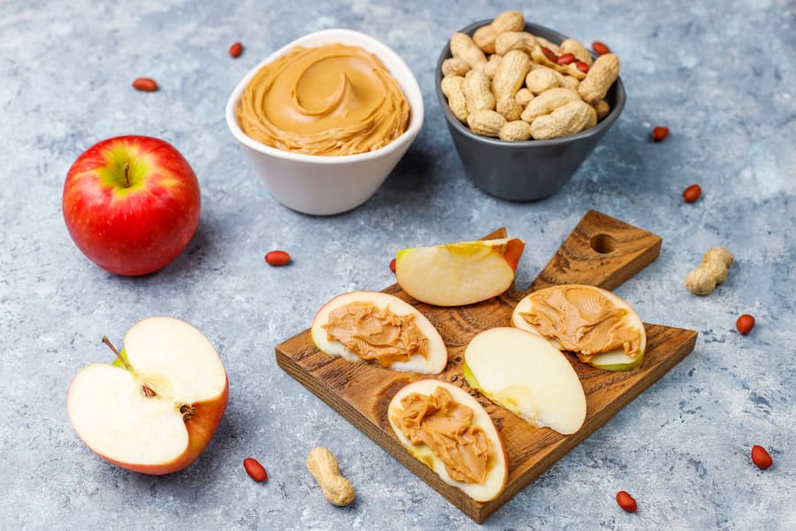 apple slices topped with peanut butter on a wooden board