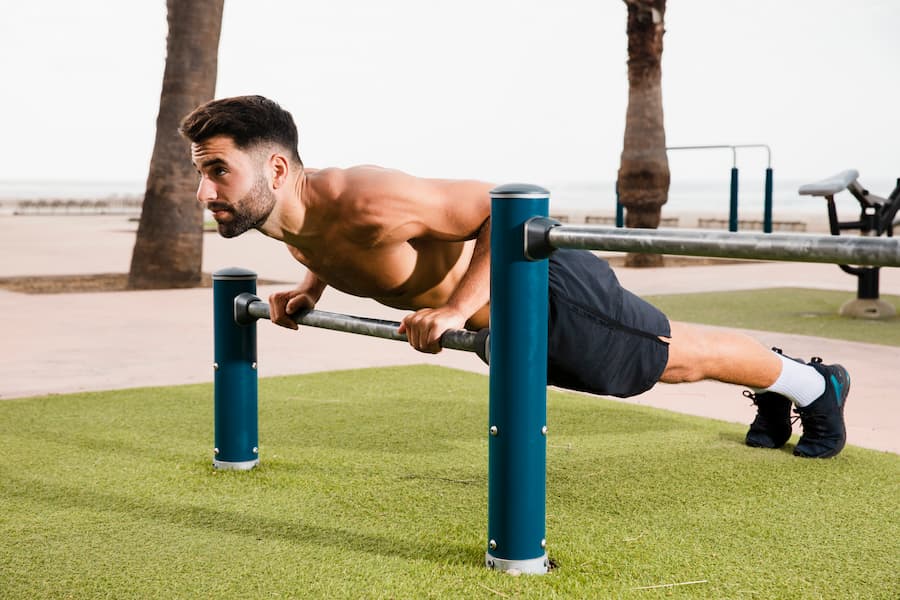 Man performing incline push-up on parallel bars