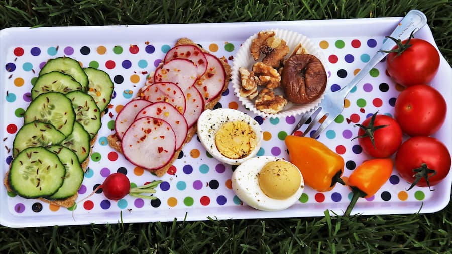 Colorful tray with sliced cucumber, radishes, boiled eggs, walnuts and tomatoes as a healthy snack plate