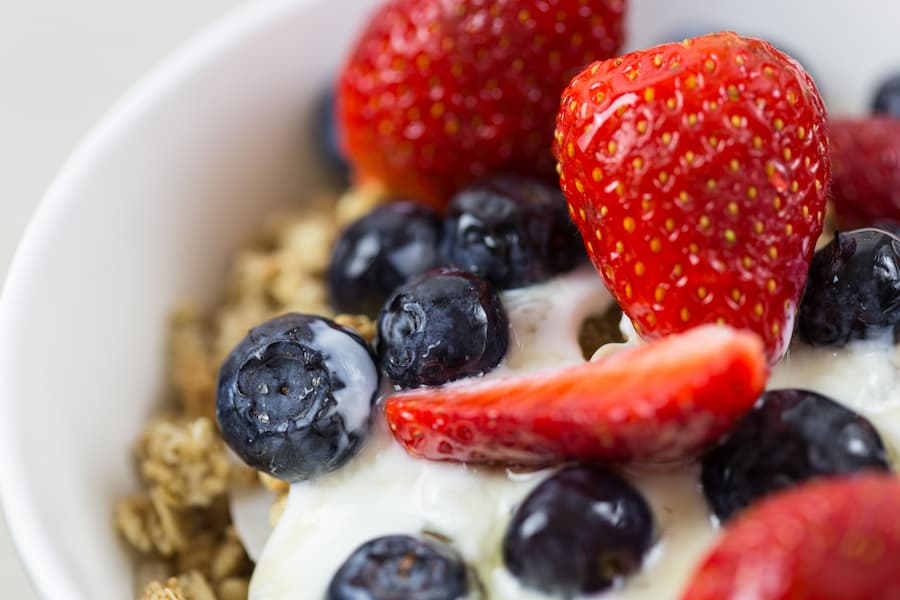 Yogurt topped with strawberries, blueberries and granola, a healthy school snack