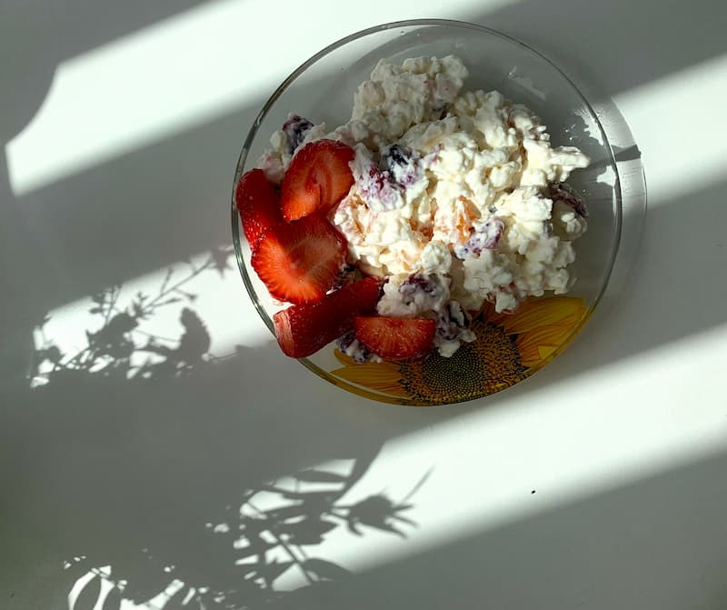 Cottage cheese in a glass bowl topped with fresh strawberries and fruit