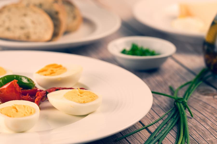 Halved hard-boiled eggs on a white plate with chives