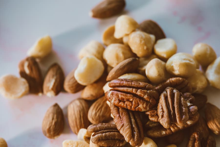 Small pile of unsalted mixed nuts including almonds, pecans and macadamia, a healthy snack for pregnant ladies