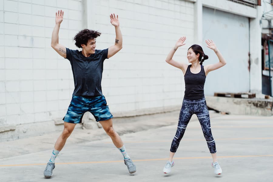 Two people doing jumping jacks as a morning warm-up exercise