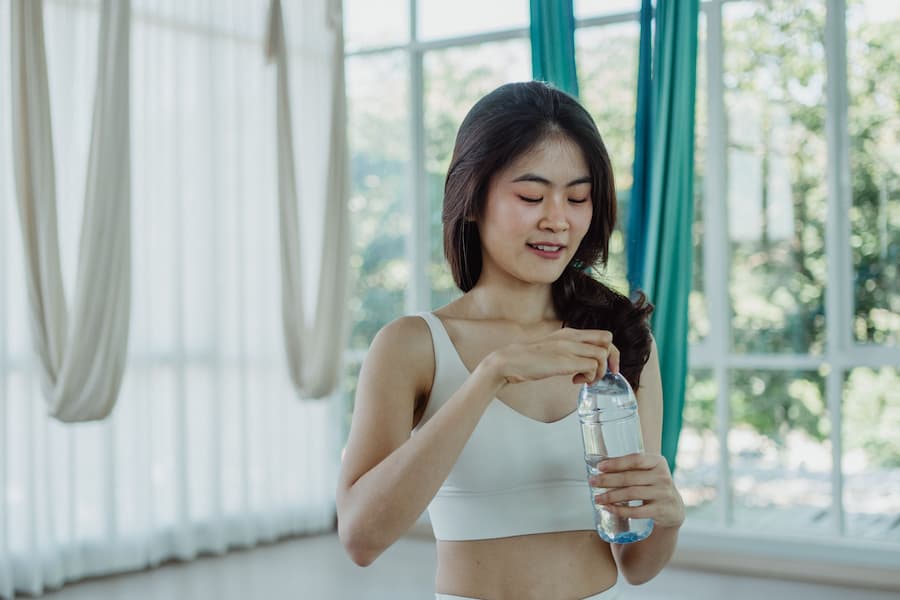 Woman opening a water bottle to stay hydrated after a workout