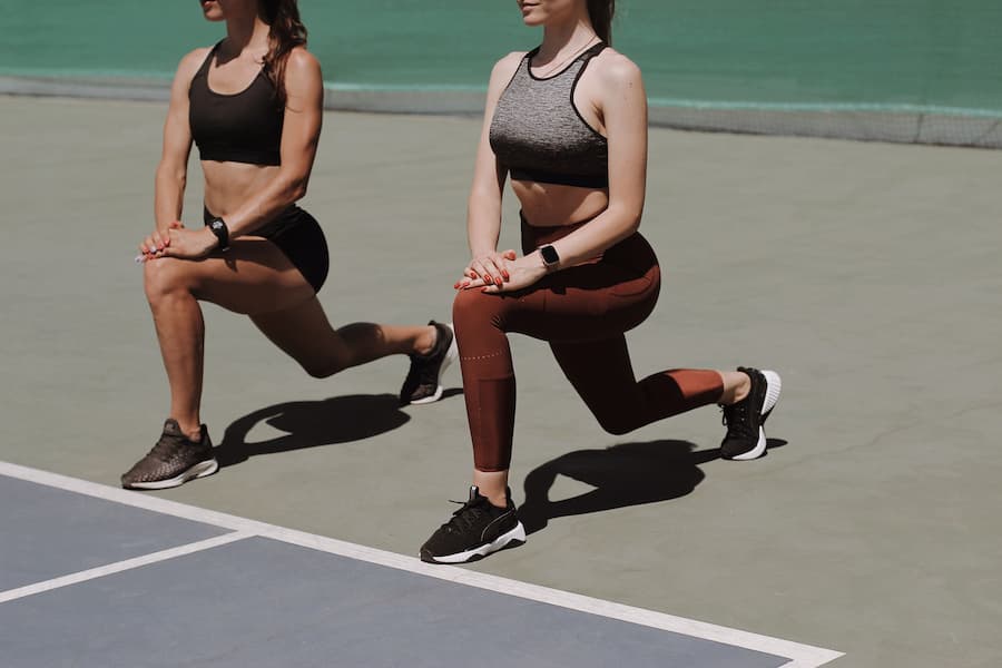 Two women doing reverse lunges outdoors