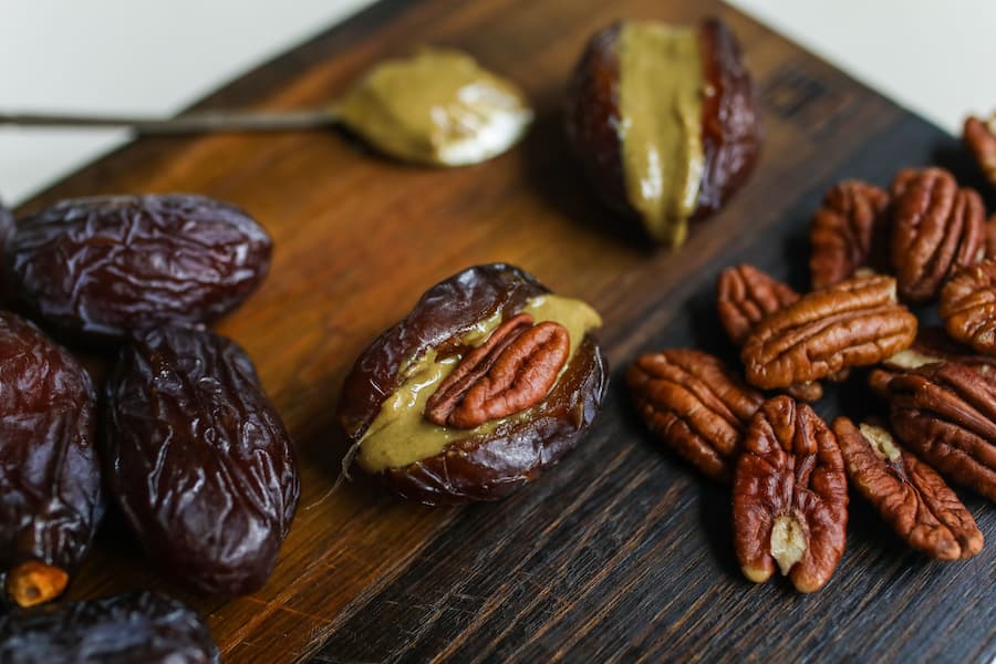 dates filled with nut butter and pecans, ingredients for no-bake date and nut bars