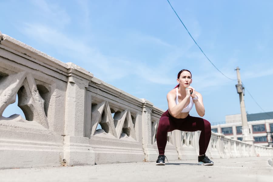 Woman doing a bodyweight squat outdoors as part of a home workout