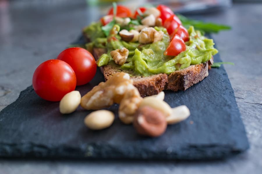 Whole-grain toast with mashed avocado, walnuts and cherry tomatoes on a slate plate