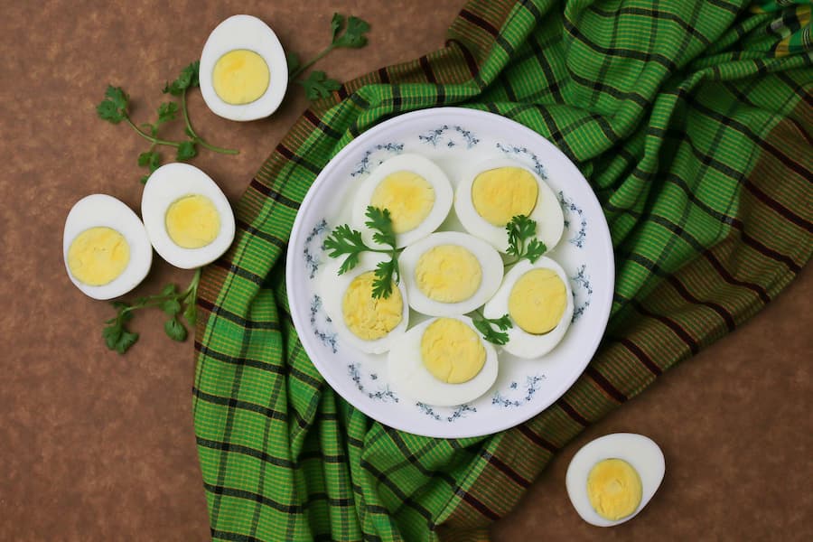 Halved hard-boiled eggs on a blue and white plate with a green checkered cloth