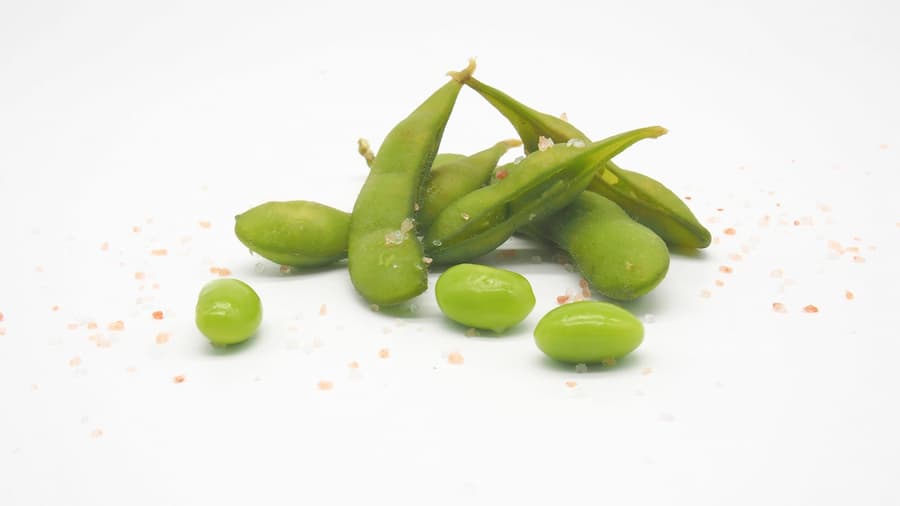 Fresh green edamame pods and beans on a white background